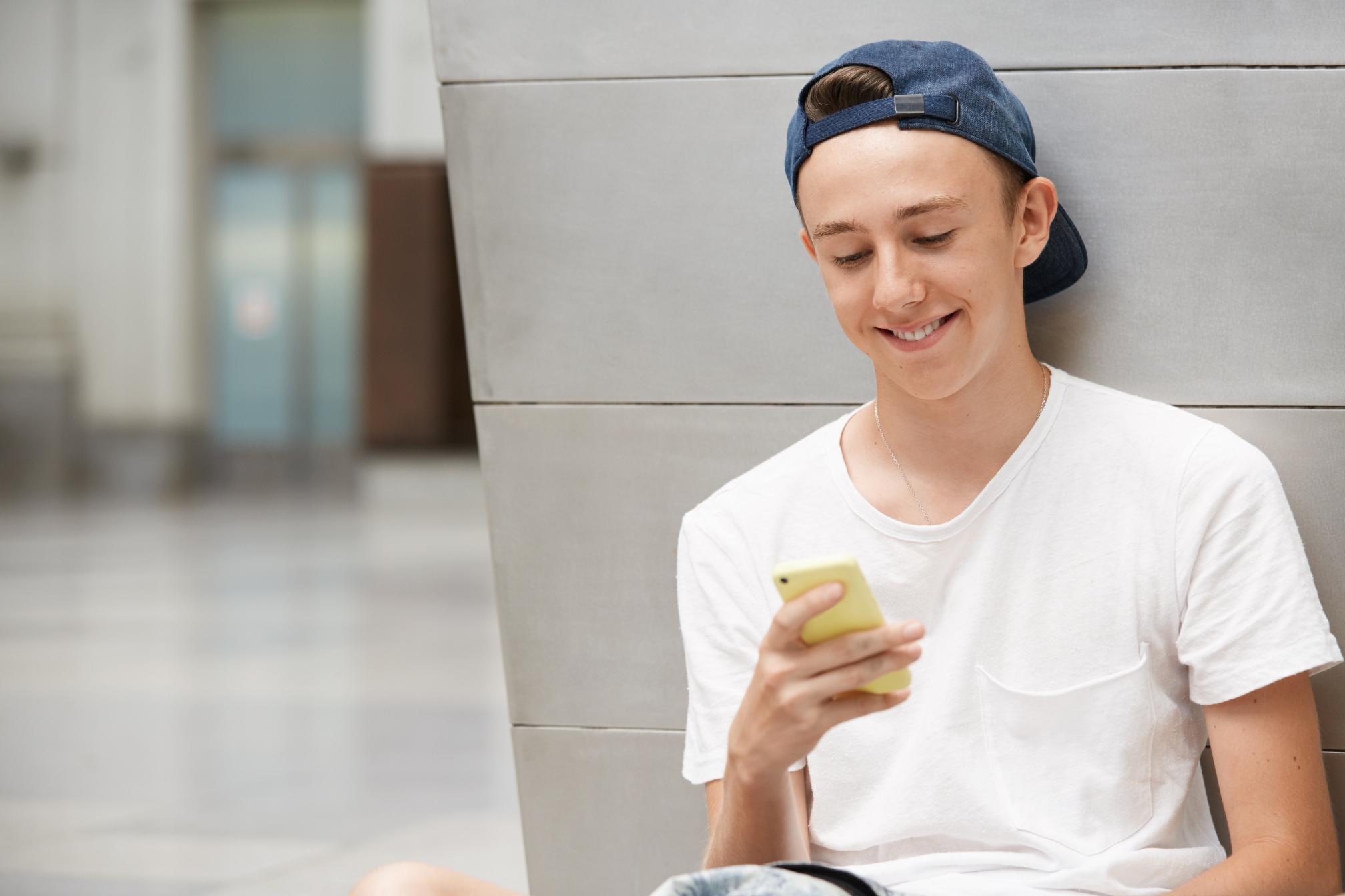 teenage boy wearing cap using smartphone kopie