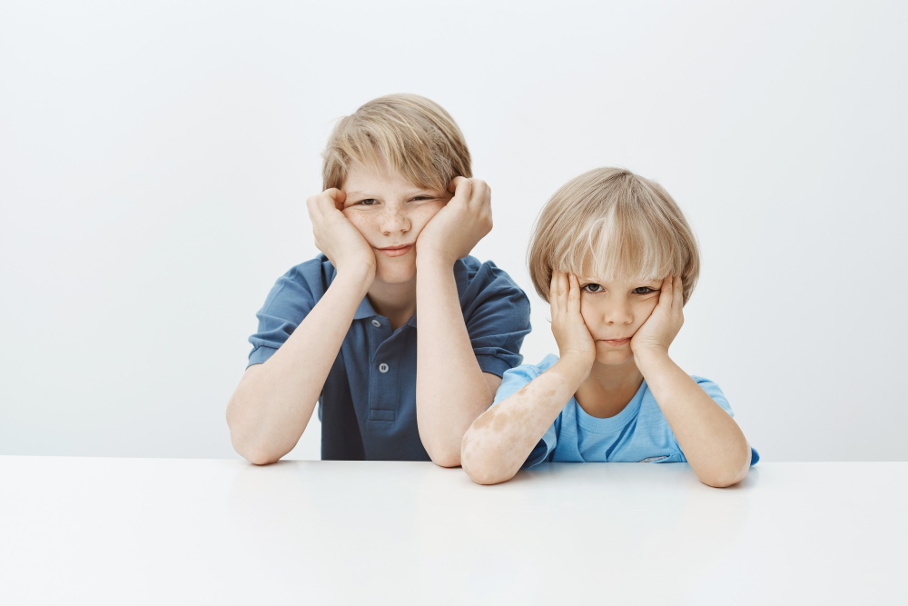 sons grounded bad behaviour school bored unhappy cute male children sitting table